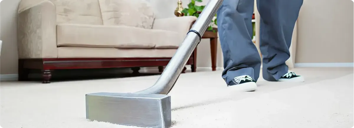 Carpet cleaning technician using a hot-water extraction wand on a light-colored carpet in a living room, San Francisco, CA.